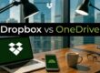 Banner comparing Dropbox vs OneDrive on a wooden desk with laptop, phone, coffee mug and glasses in a city office setting.