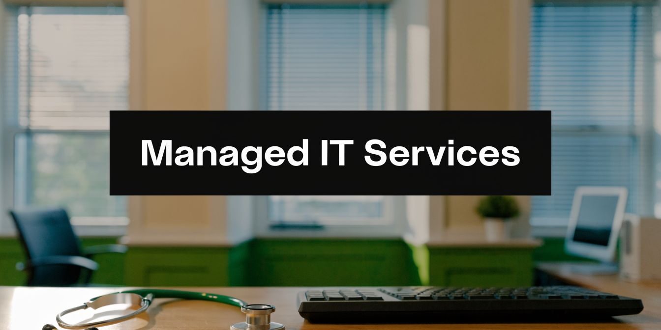 Banner reads 'Managed IT Services' over a modern office desk with a keyboard, stethoscope, and laptop in the background.