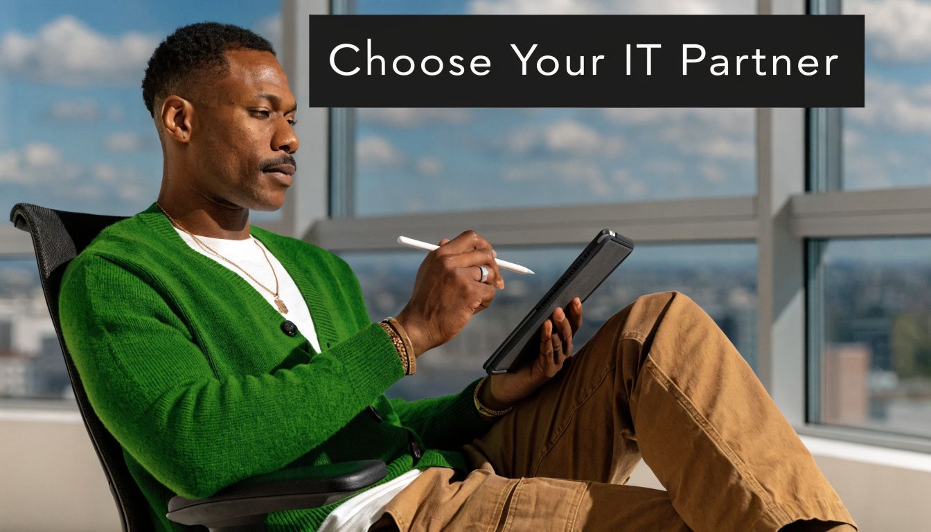 A professional man sitting in a sunny office, using a stylus to work on a digital tablet.