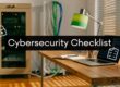 Office desk scene with a laptop displaying a 'Cybersecurity Checklist' overlay and a notebook, lamp, and cables in the background.