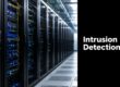 Rows of server racks in a data center with blue/yellow cables, beside a black panel that says 'Intrusion Detection'.