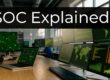 A data operations center with multiple monitors displaying maps and graphs, overlaid by the words 'SOC Explained'.