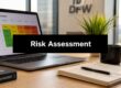 Laptop on a wooden desk showing a risk assessment matrix on screen, with a notebook, pen and mug nearby; large 'Risk Assessment' banner across the image.