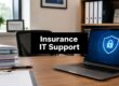 Office desk with a bold sign reading 'Insurance IT Support' in front of a laptop displaying a blue shield security graphic on the screen.