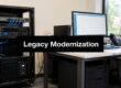 Server rack and workstation in an office, with a bold banner reading 'Legacy Modernization' across the center of the image.