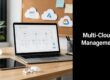 Laptop on a wooden desk shows a cloud diagram; tablet, mug, plant, and a corkboard with AWS, Azure, and Google Cloud icons in the background; black panel reads 'Multi-Cloud Management'