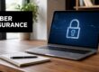 Laptop on a wooden desk showing a glowing padlock; banner says CYBER INSURANCE.