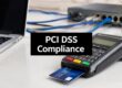 Payment terminal with a credit card inserted on a desk, overlaid with 'PCI DSS Compliance' text (informing security compliance in payments).