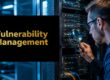 IT professional in a data center inspects a server rack with a magnifying glass near a 'Vulnerability Management' panel.