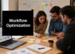 Team of three professionals collaborates around a table with sticky notes, a laptop, and notebooks for a workflow optimization session.